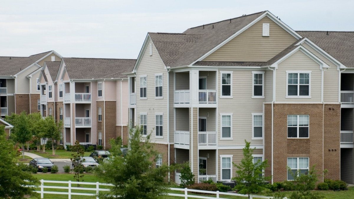 Garden style apartment buildings stand behind a white fence and parking lot, places apartment injury lawyers in Summerville examine