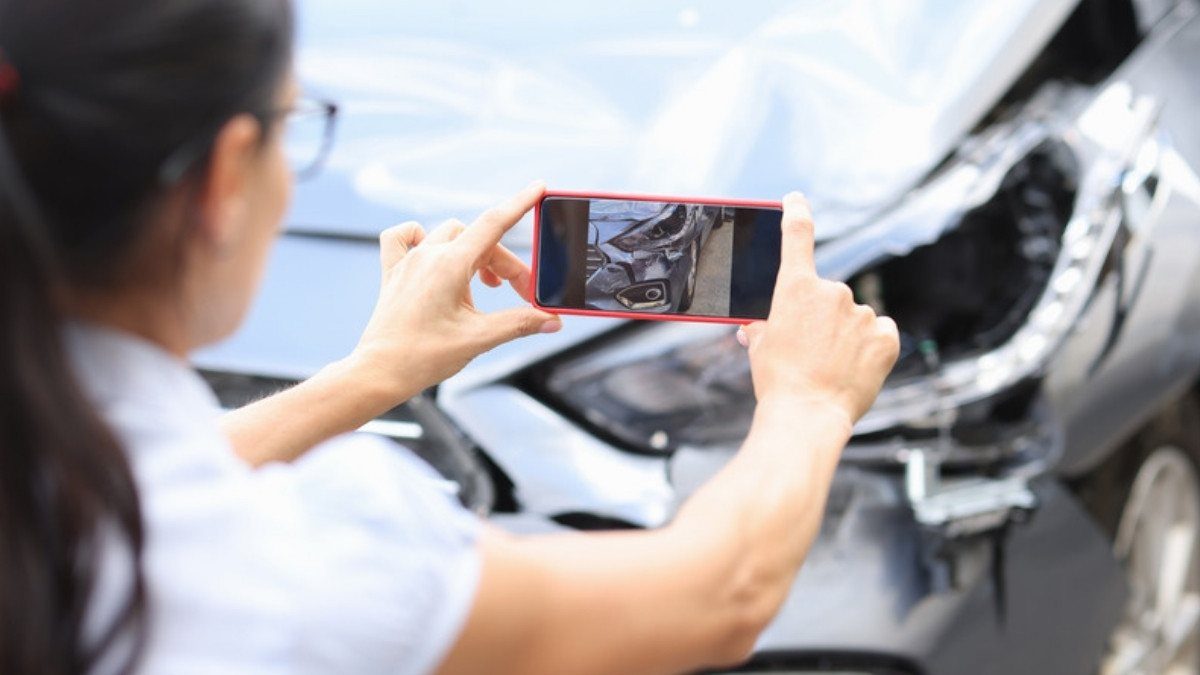 A woman photographs a damaged headlight with her phone, gathering proof that can help when there is no police report