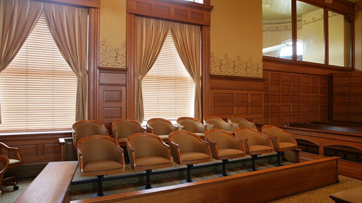 In a wood paneled courtroom, two rows of empty jury chairs wait for the jurors who compare each driver's share of fault