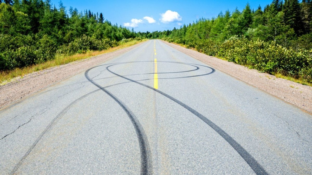 Curving black tire marks cross a two lane road with a yellow center line, physical evidence that can show how fast a car moved
