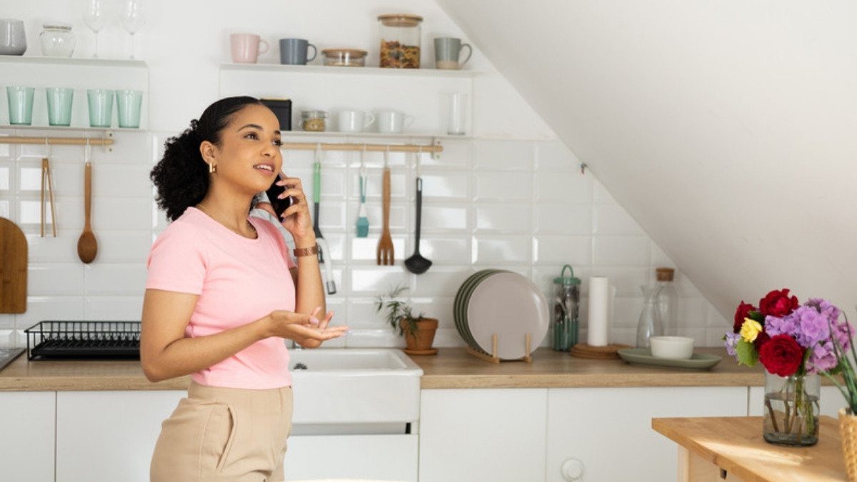 A young woman talks on her phone in a bright kitchen, the kind of quick call people make to car accident lawyers in Charleston County