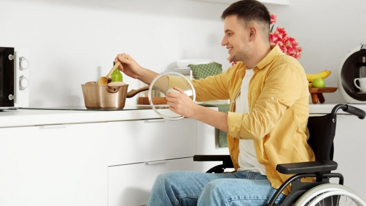 A young man in a wheelchair stirs a pot in his kitchen, the daily life catastrophic injury attorneys in Summerville plan a claim around