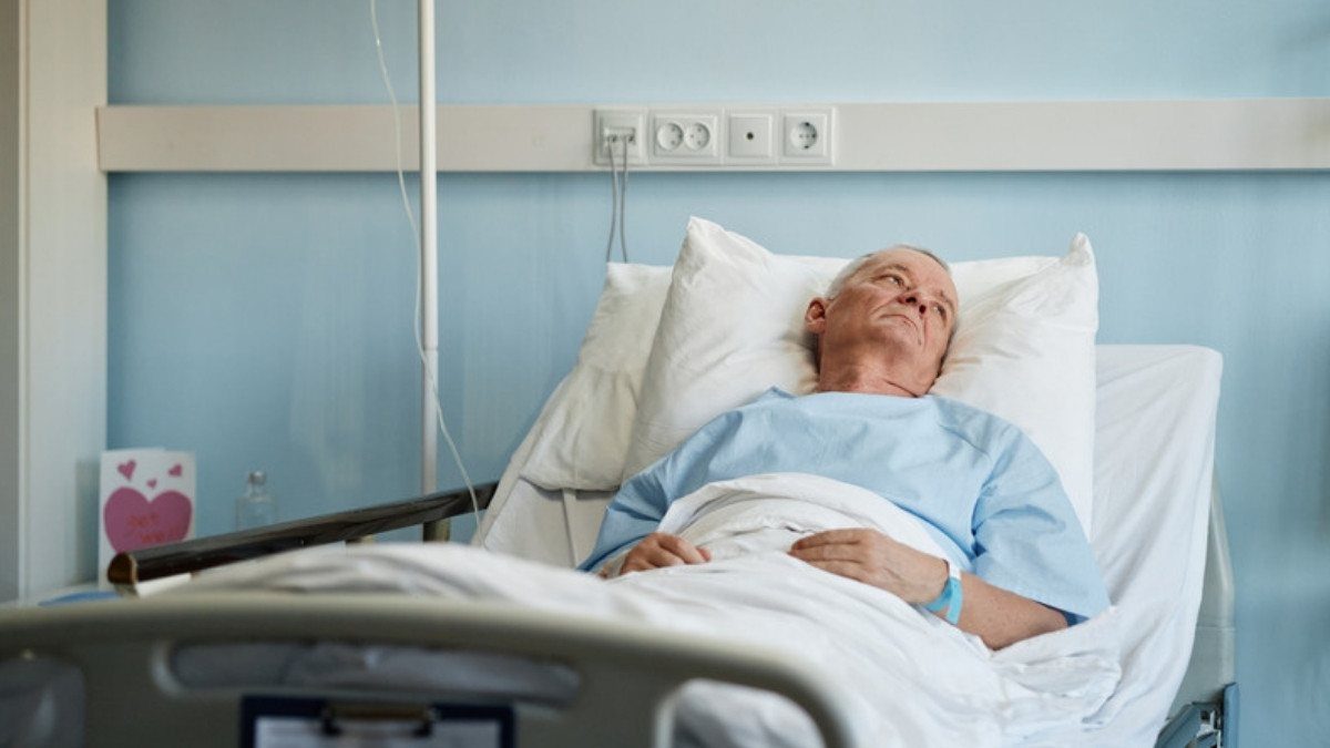 An older man rests in a hospital bed with an IV line, a recovery catastrophic injury attorneys in Summerville measure in years