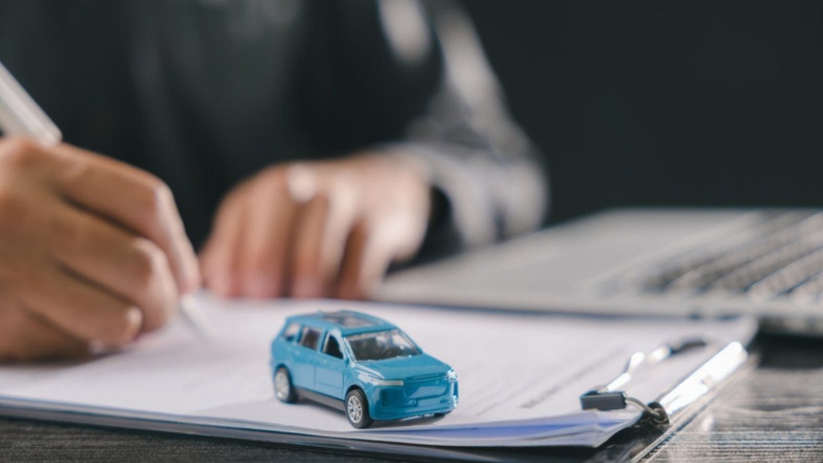 A pen signs an auto policy under a small toy car, the coverage limits catastrophic injury attorneys in Summerville map before any talks