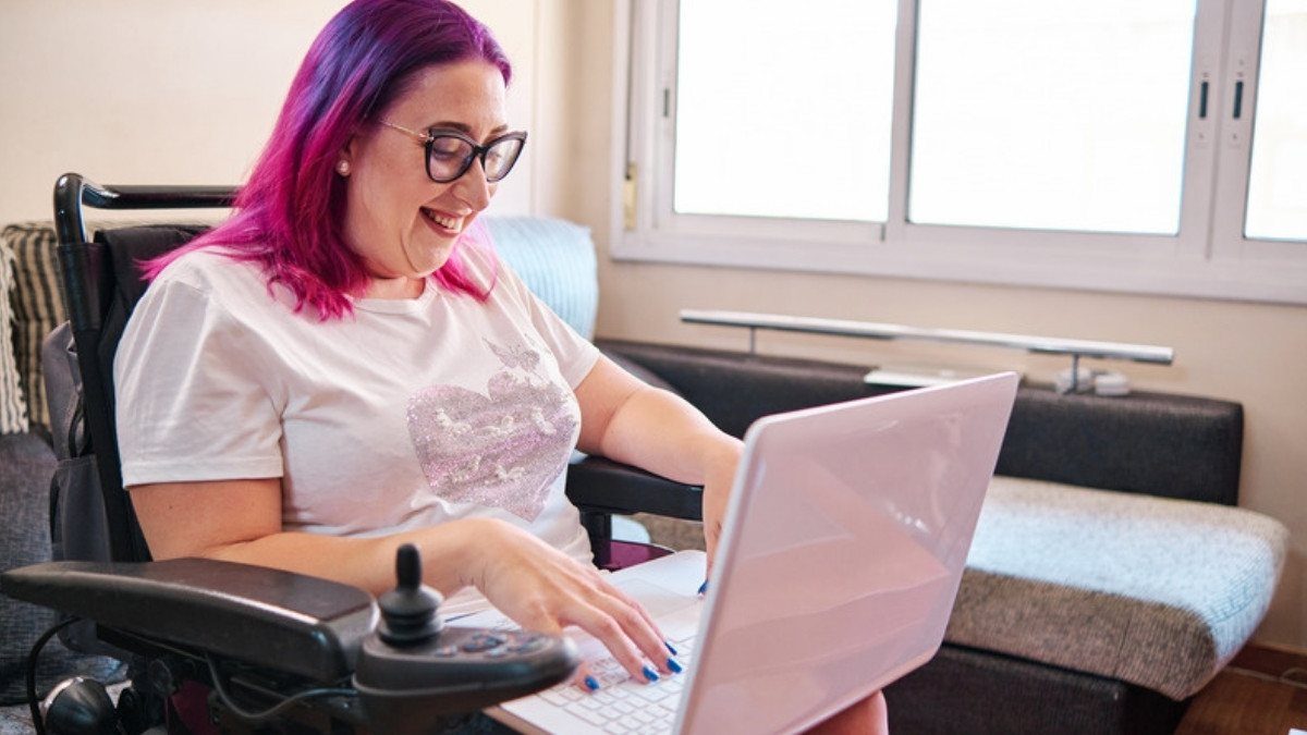 A woman in a power wheelchair works on a laptop at home, the care and work catastrophic injury attorneys in Summerville account for