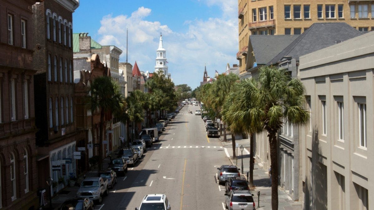 Cars line a palm shaded downtown street below a white steeple, the city traffic Charleston personal injury lawyers see in reports