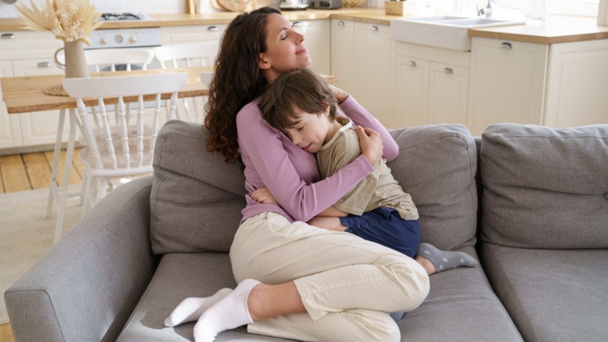 A mother holds her son close on a gray sofa at home, the kind of family child dog bite injury lawyers in Summerville hear from