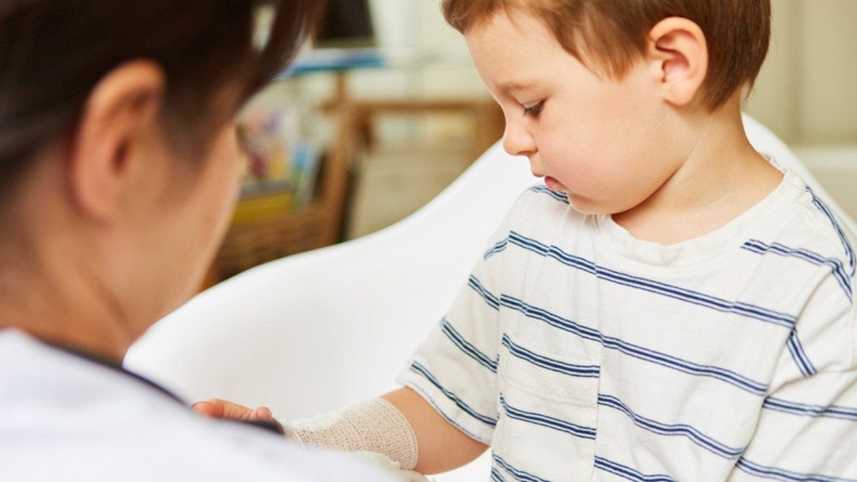 A pediatrician wraps a bandage around a young boy's arm, a visit child dog bite injury lawyers in Summerville ask families to document
