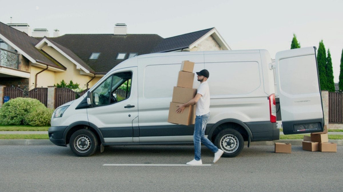 A driver carries stacked boxes from a white van on a quiet street, a route delivery truck accident lawyers in Summerville retrace