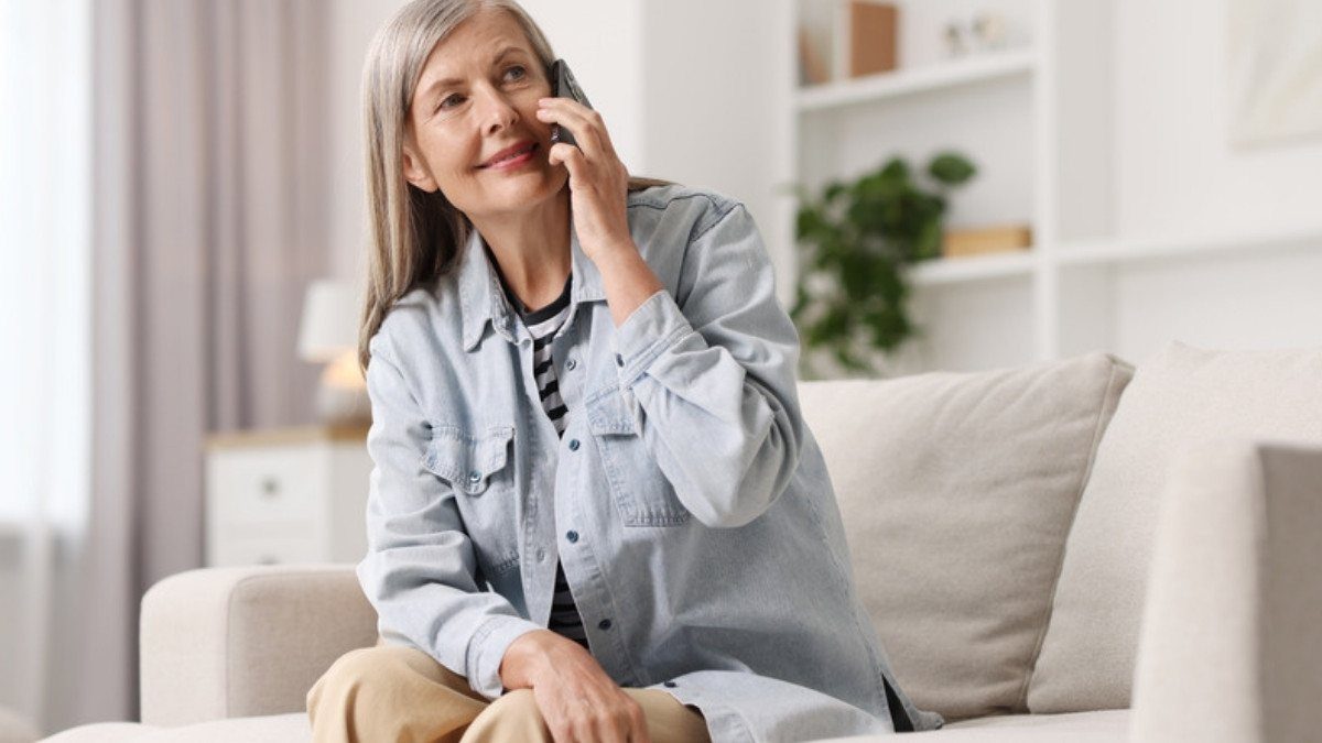 A woman smiles on a light sofa during a phone call at home, a simple way to reach distracted driving accident lawyers in Summerville