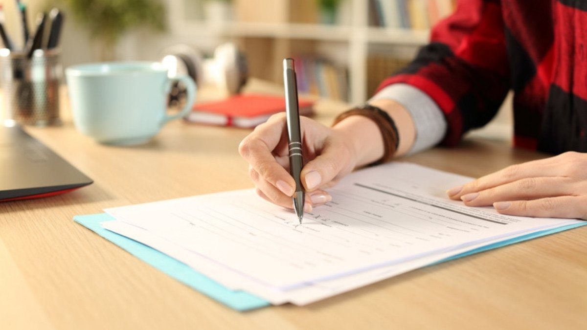 Hands fill out a form at a home desk beside a mug, paperwork dog bite attorneys in Summerville can review before an insurer sees it