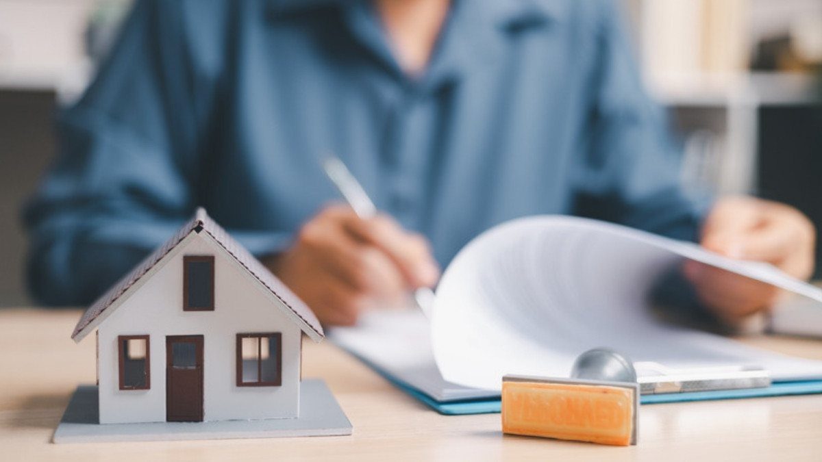 A person signs papers beside a small model house, the homeowner policy dog bite insurance claim lawyers in Summerville look to first
