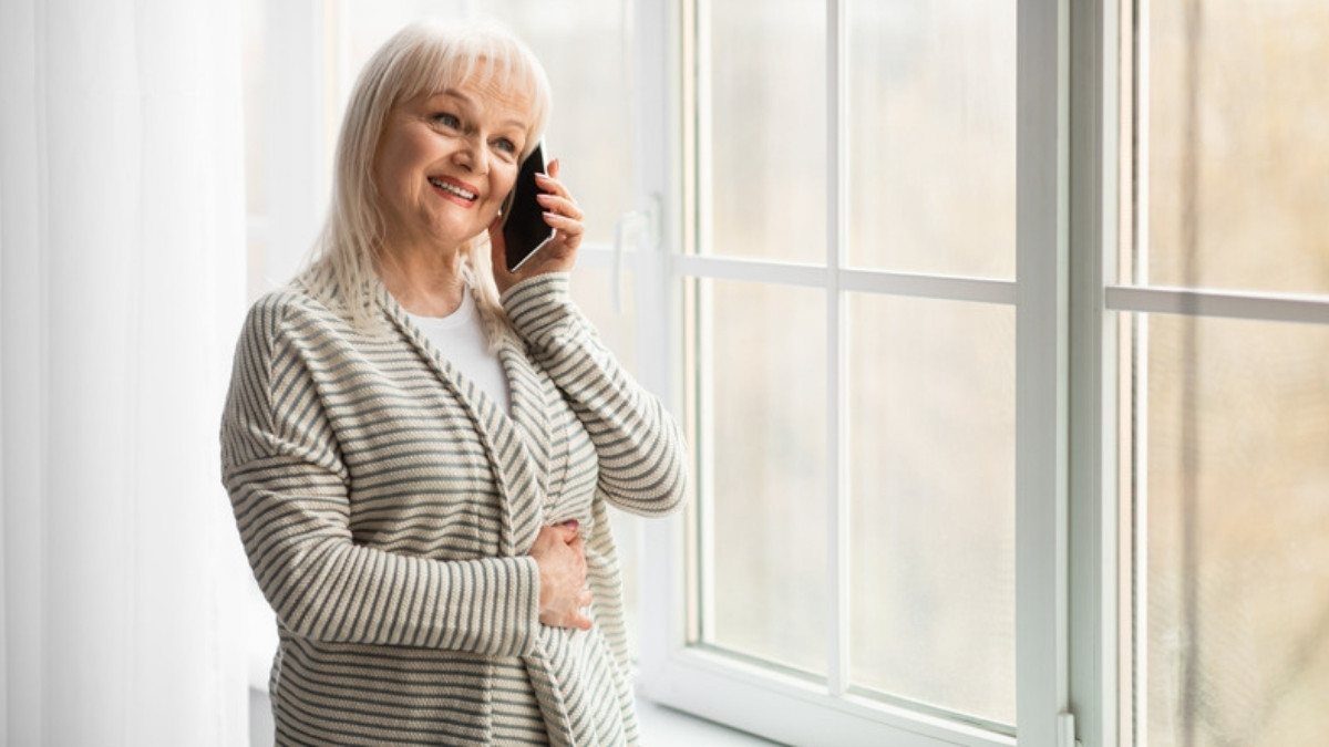 A woman talks on her phone by a sunny window at home, a calm moment to reach drunk driving accident lawyers in Summerville