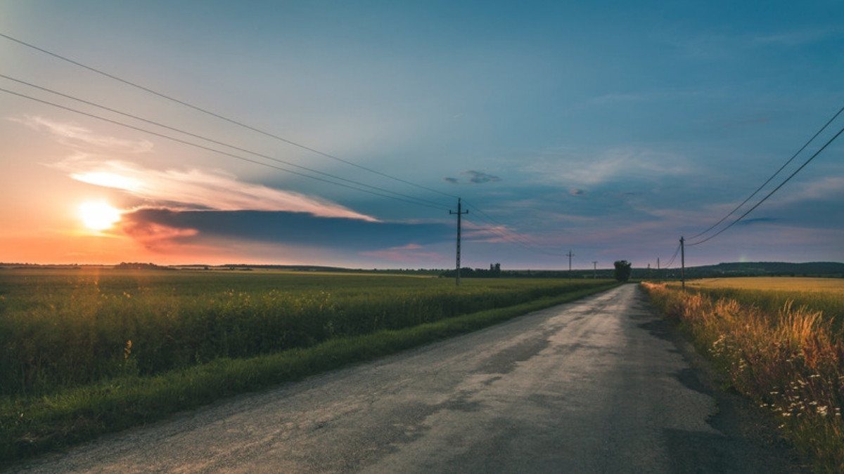An empty country road runs between quiet fields at sunset, the kind of rural route fatal car accident lawyers in Summerville review
