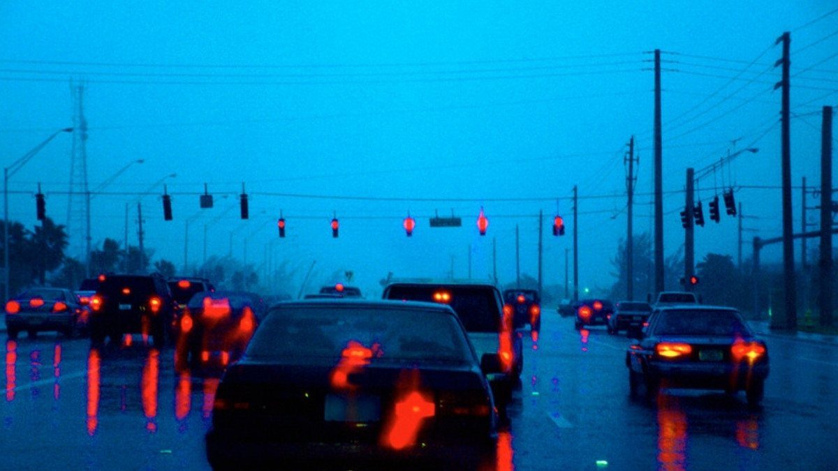 Brake lights glow on a rain soaked multilane road at dusk as traffic waits at signals, a scene Goose Creek car accident lawyers know