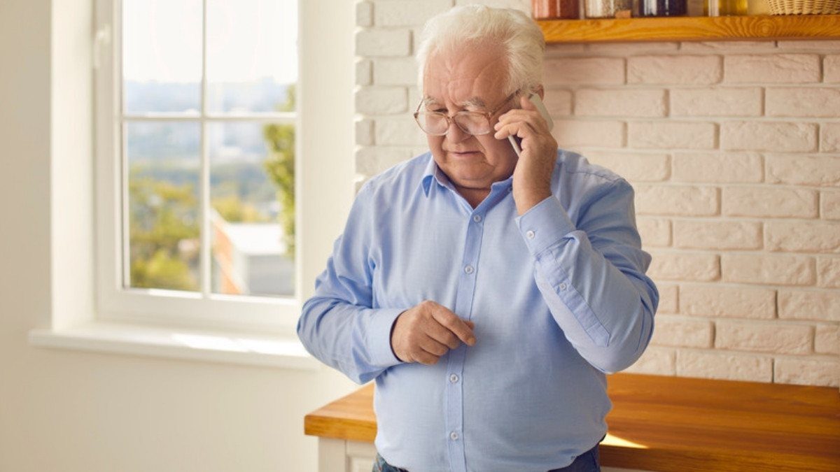 An older man makes a call in his sunny kitchen, an easy way to reach hit and run accident lawyers in Summerville about a UM claim
