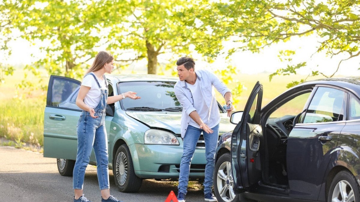 Two drivers argue beside dented cars and a warning triangle, the kind of shared blame dispute comparative negligence rules divide
