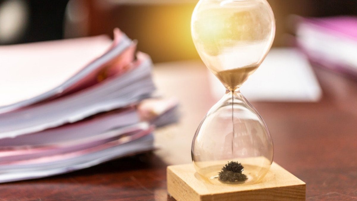Sand runs through an hourglass beside a stack of paper files, a reminder that each car accident case moves at its own pace