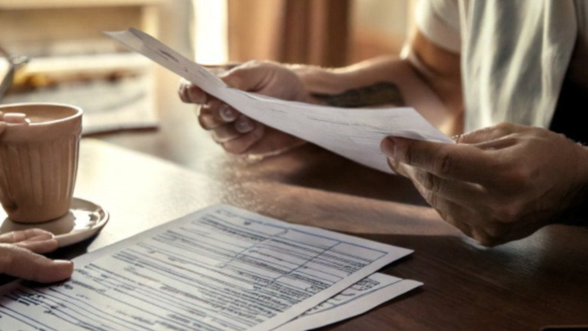 Hands hold a printed form over a table with coffee nearby, the way many people read over a copy of their accident report