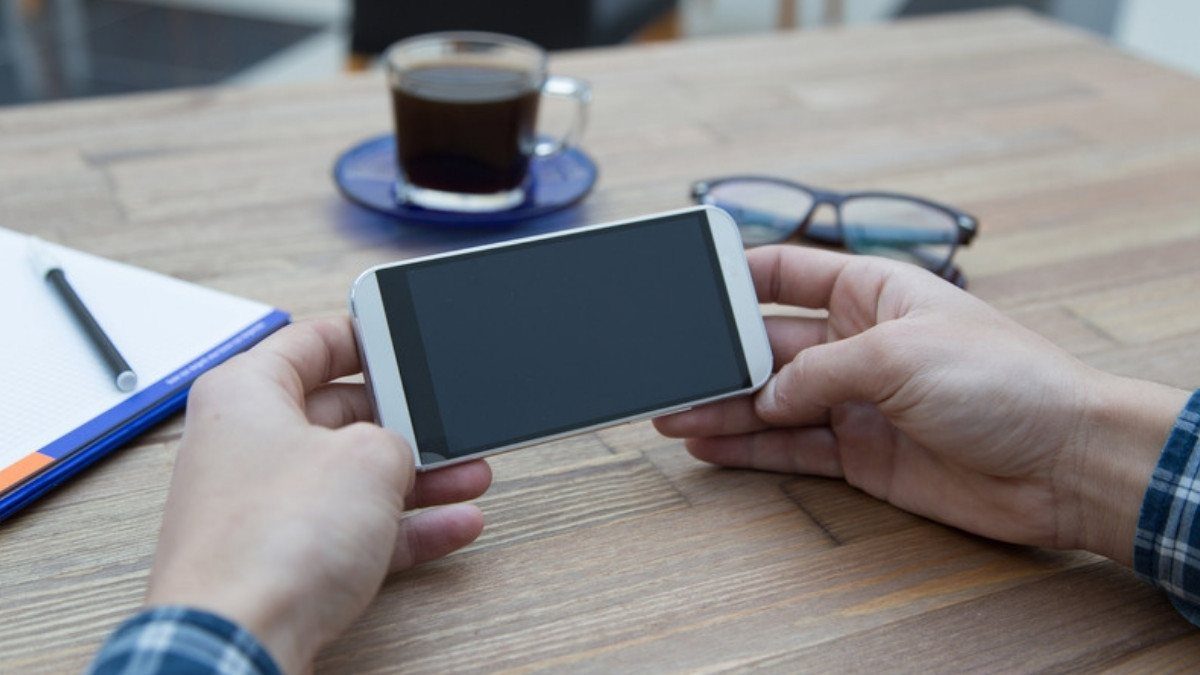 Hands hold a phone over a wooden table with coffee and a notebook, ready to call Lyft accident lawyers in Summerville with questions