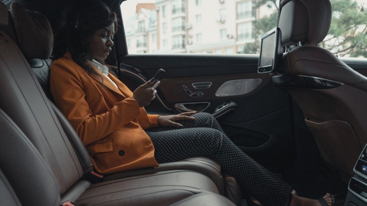 A passenger in an orange coat reads her phone in the back seat, the seat Lyft accident lawyers in Summerville ask about first