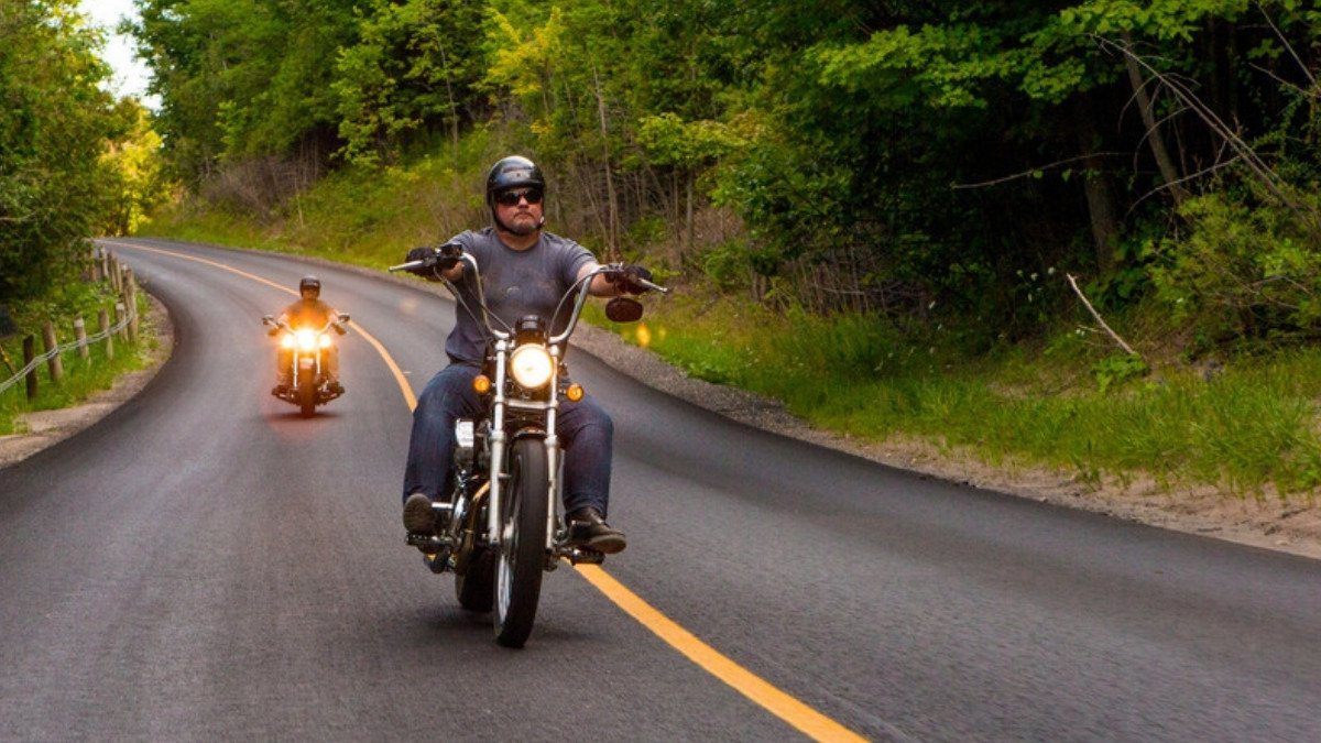 Two riders lean through a curve on a wooded country road, the kind of ride motorcycle accident lawyers in Berkeley County know