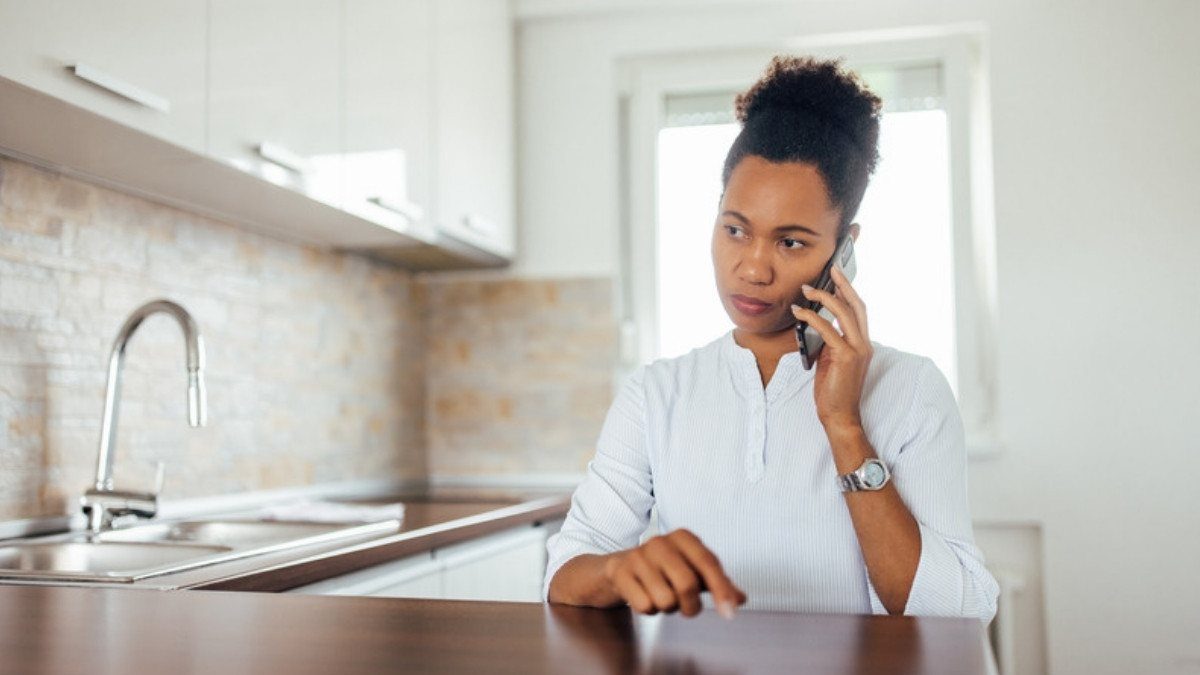 A woman sits at her kitchen table on a phone call, an easy first step toward Mount Pleasant car accident lawyers after a wreck