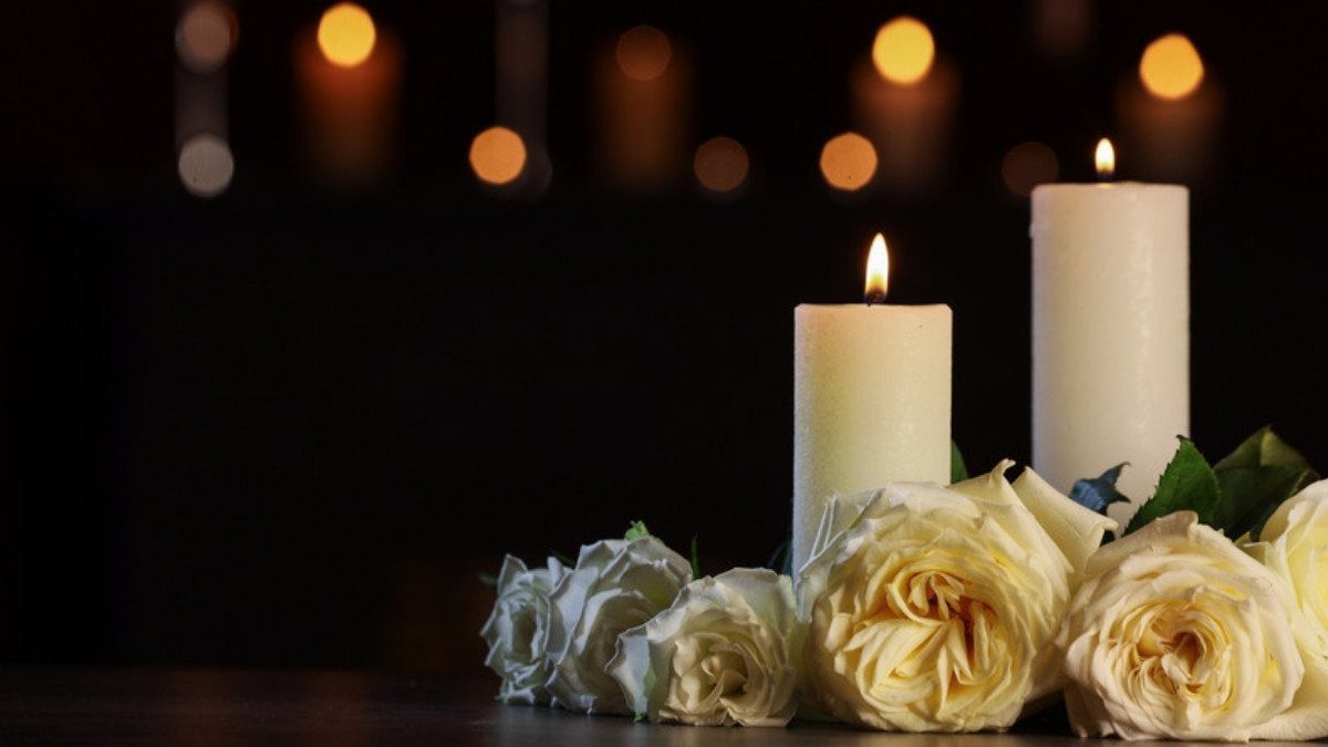 Two white candles glow beside pale roses, a quiet tribute for families who turn to pedestrian accident attorneys in Summerville