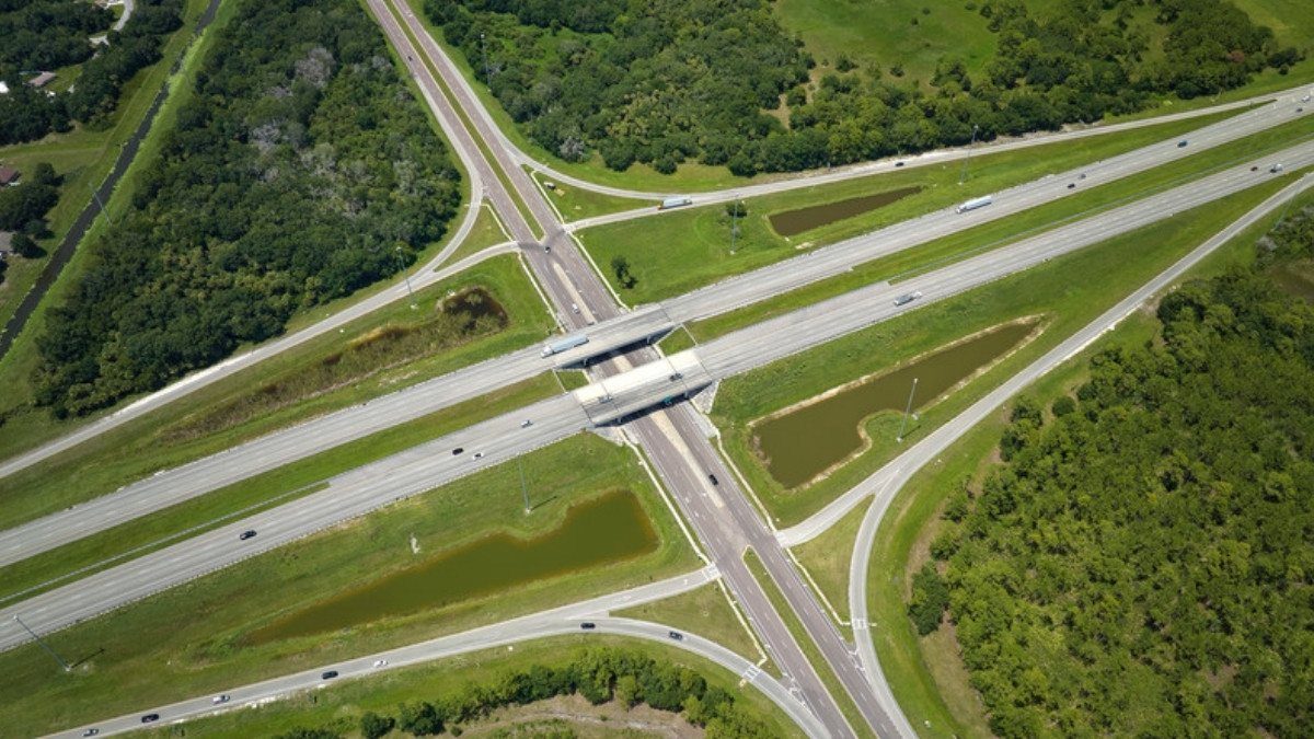 Ramps curve through green woods at an interstate interchange where personal injury attorneys in Berkeley County study merge crashes