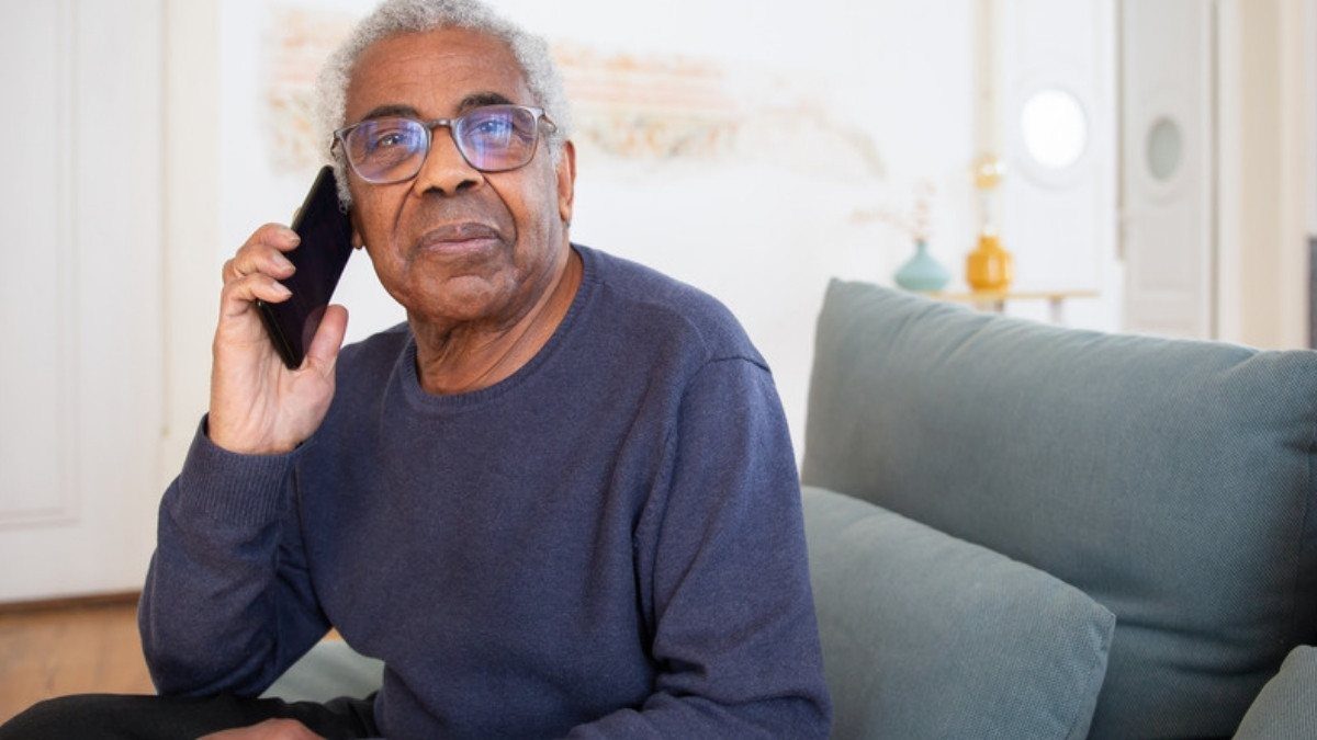 An older man sits on his sofa with a phone to his ear, ready to talk through what happened in his crash