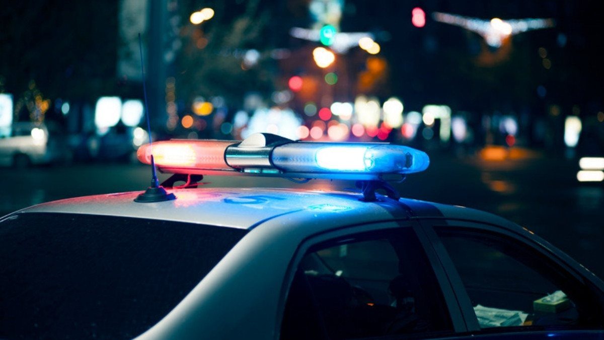 A patrol car light bar flashes red and blue on a city street at night, a reminder that each agency keeps its own crash reports