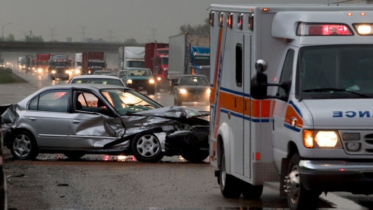 An ambulance stops beside a wrecked sedan on a rainy highway, a serious crash personal injury attorneys in Charleston County often see