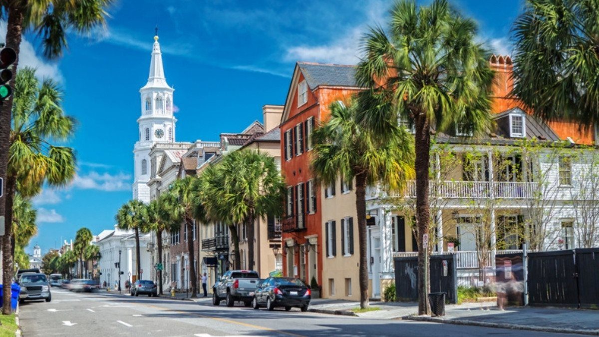 Palmettos line Broad Street in downtown Charleston as the white steeple of St. Michael's Church rises against a blue sky