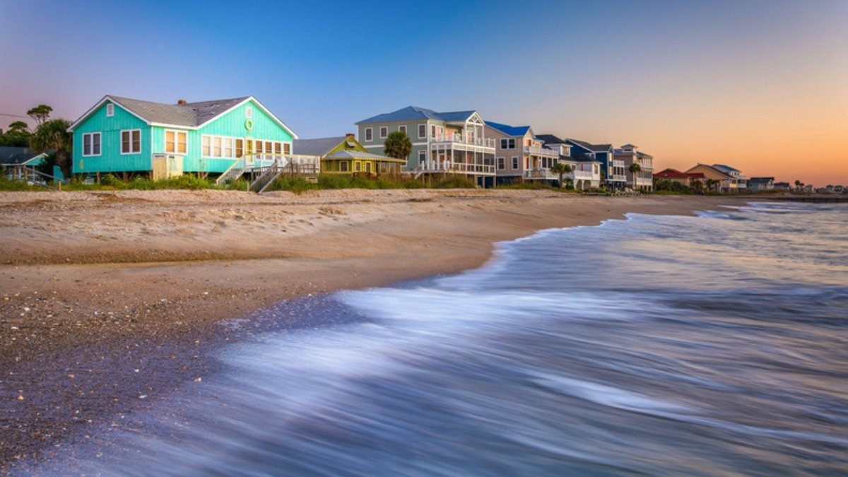 Beachfront homes line the shore at sunrise as waves wash onto the sand at Edisto Beach, South Carolina