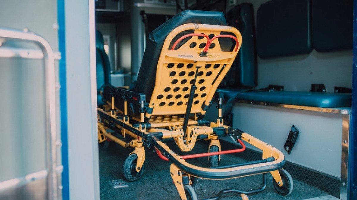 An empty yellow stretcher waits inside an ambulance, where the medical record of a serious crash injury often begins