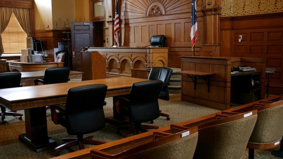 An empty wood paneled courtroom with counsel tables and flags, a setting personal injury attorneys in Georgetown County prepare for