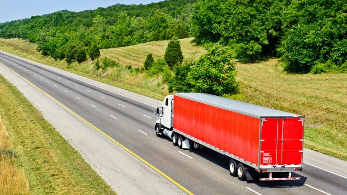 A red tractor trailer rolls down a divided interstate, where personal injury attorneys in Orangeburg County often trace truck claims