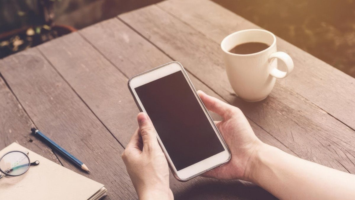 Hands hold a phone over a wooden table with coffee and a notebook, ready to reach personal injury attorneys in Williamsburg County