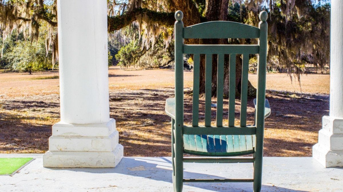 A green rocking chair waits on a columned porch under mossy oaks, a calm spot to call premises liability lawyers in Summerville