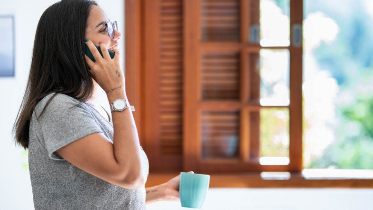 A woman with a mug talks on the phone by a sunny window, a quiet moment to ask retail slip and fall lawyers in Summerville a question