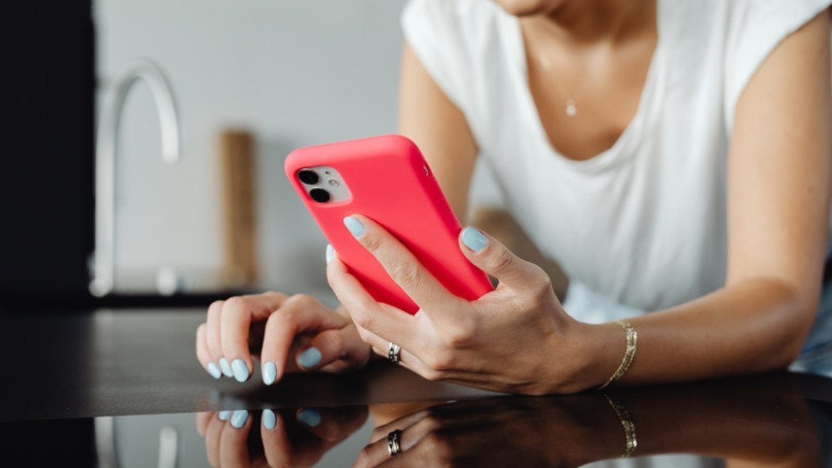 Hands hold a red smartphone at a kitchen counter, ready to share fall photos with slip and fall attorneys in Summerville