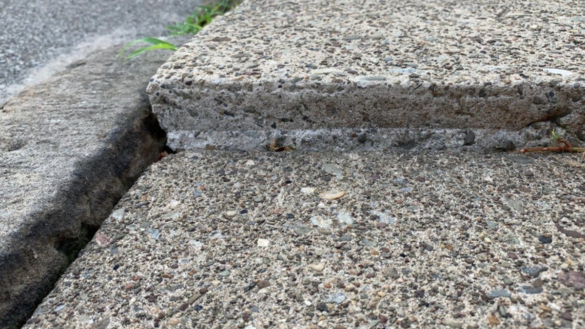 A raised concrete slab juts above the next section of sidewalk, a trip hazard slip and fall attorneys in Summerville photograph