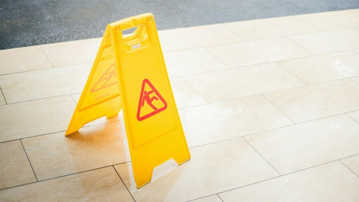 A yellow wet floor sign stands on sunlit tile, the kind of warning slip and fall attorneys in Summerville look for after a fall