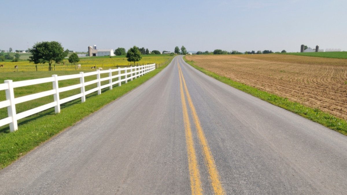 A two lane road runs past a white fence and plowed fields, a rural route where South Carolina personal injury attorneys see crashes