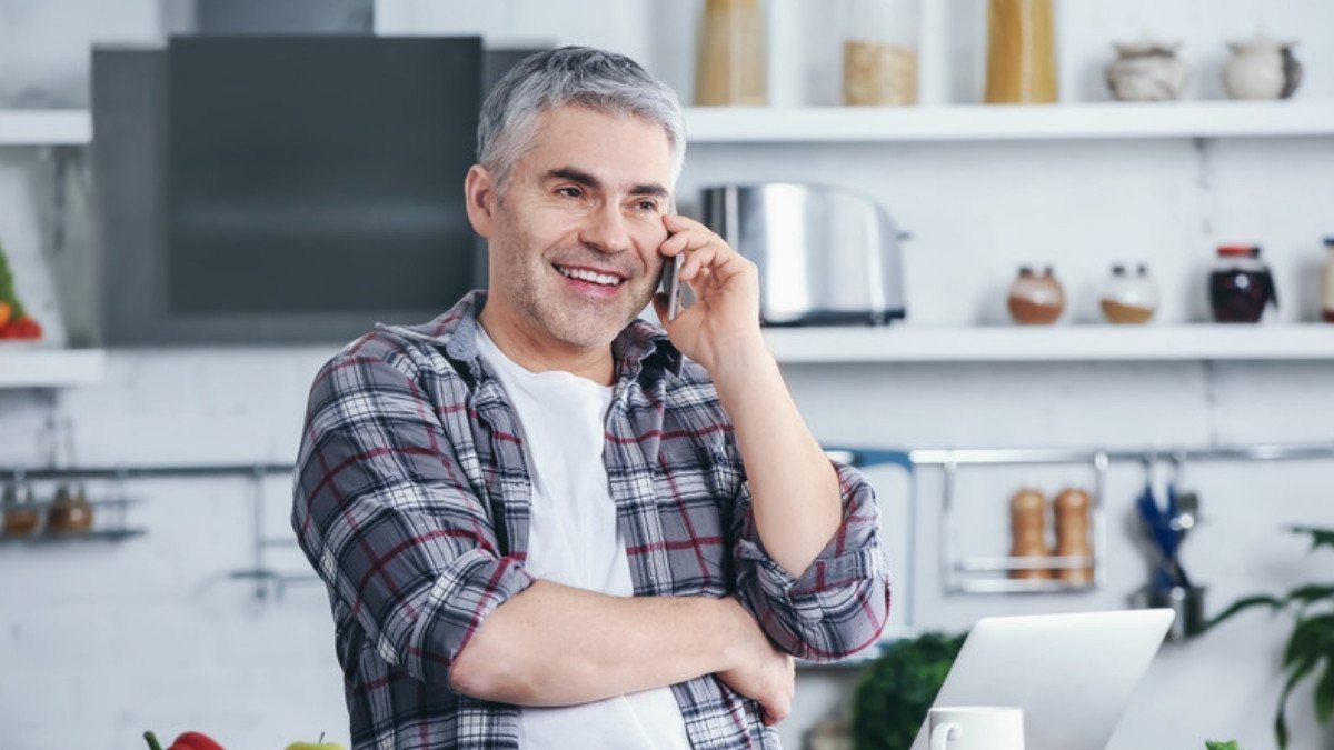 A gray haired man talks on the phone in his kitchen, the kind of call tractor trailer accident lawyers in Summerville take
