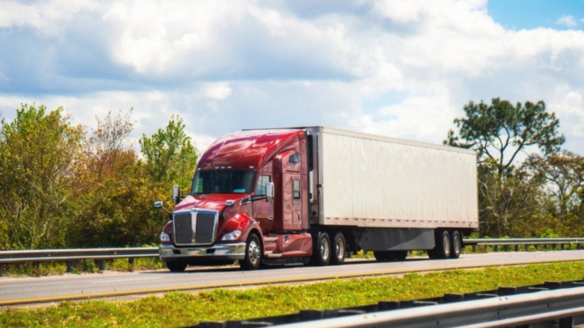 A red semi truck pulls a white trailer down a divided highway, the kind of rig truck accident attorneys in Summerville often see