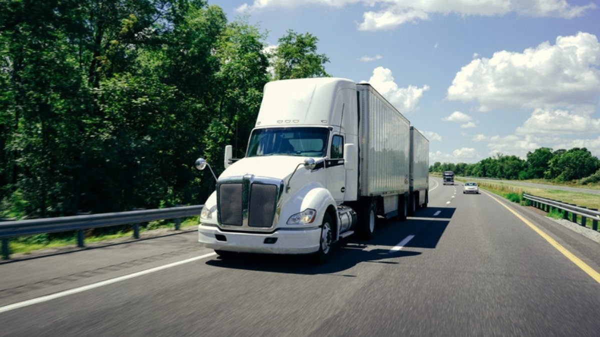 A white semi pulling double trailers runs down a divided highway, the type of rig truck accident lawyers in Berkeley County investigate