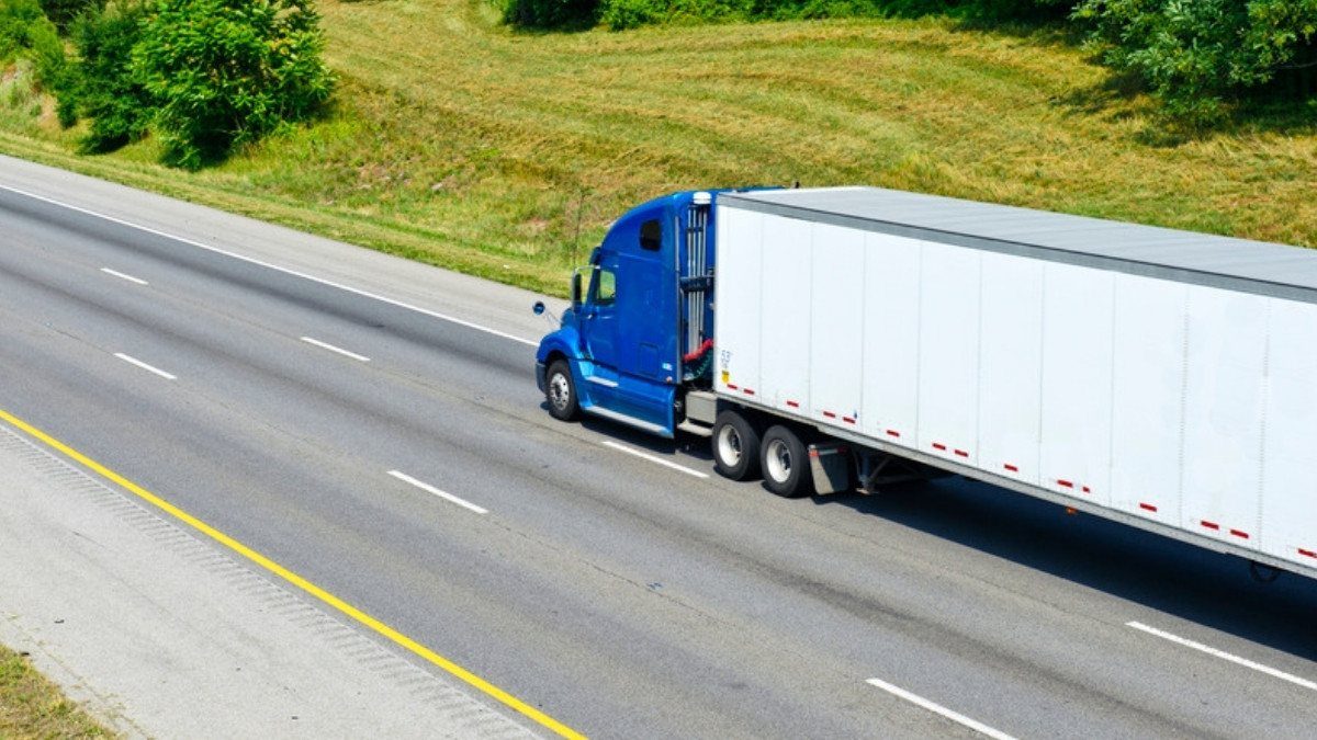 A blue semi truck pulls a white trailer down an interstate, the kind of rig truck accident lawyers in Charleston County investigate