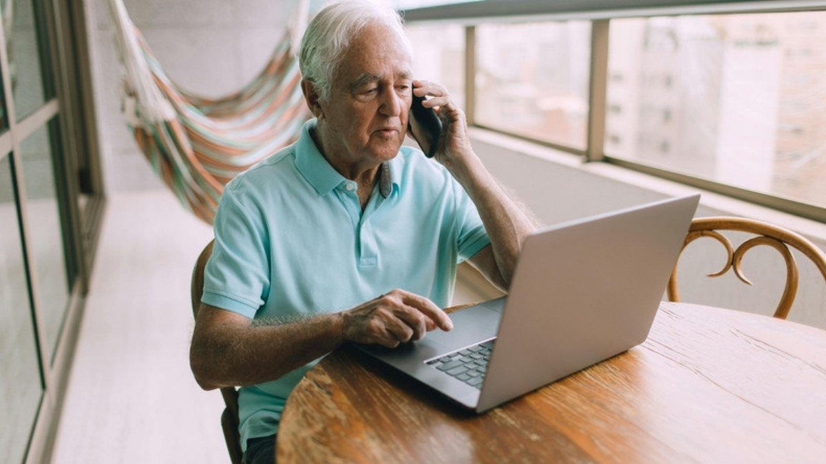 An older man talks on his phone beside an open laptop, a calm way to bring questions to truck accident lawyers in Charleston County