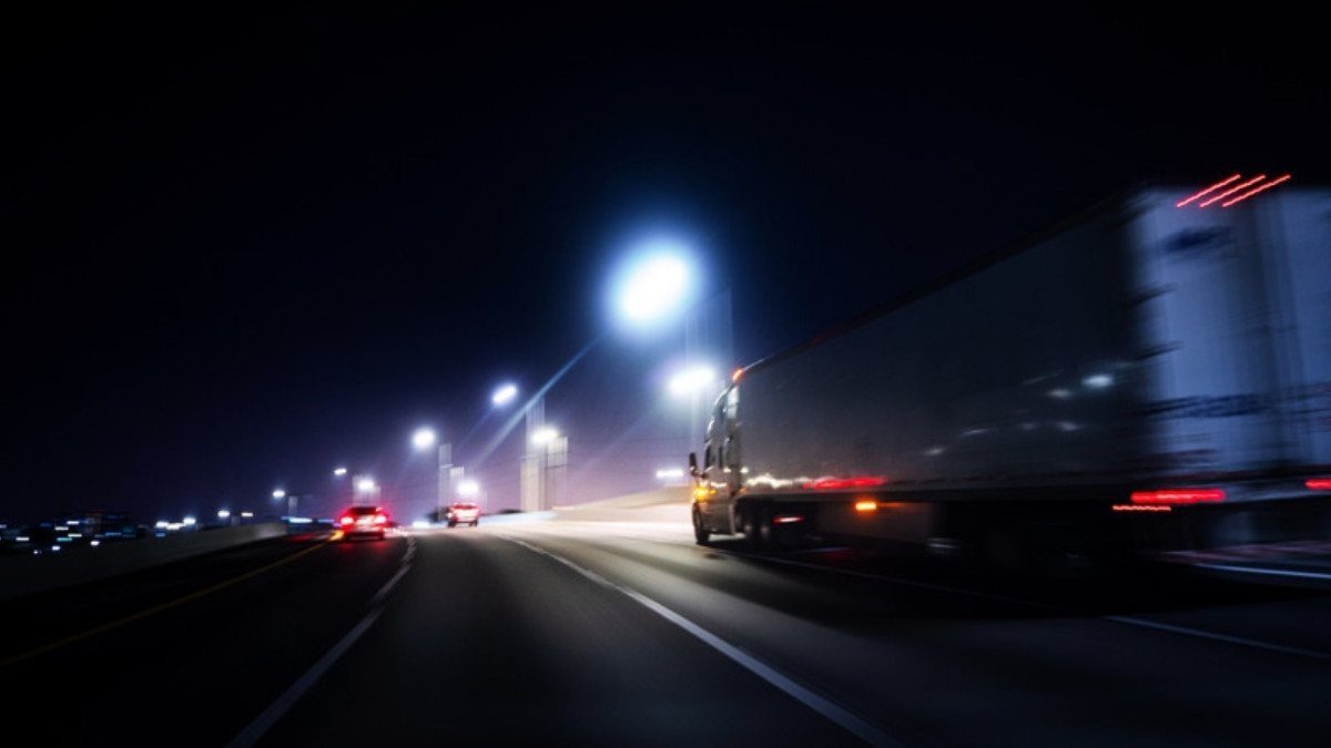 A semi truck streaks past highway lights at night, the late hours truck driver fatigue accident lawyers in Summerville look into